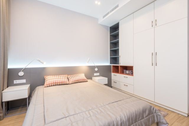 A bedroom with white fitted wardrobes and built-in shelving