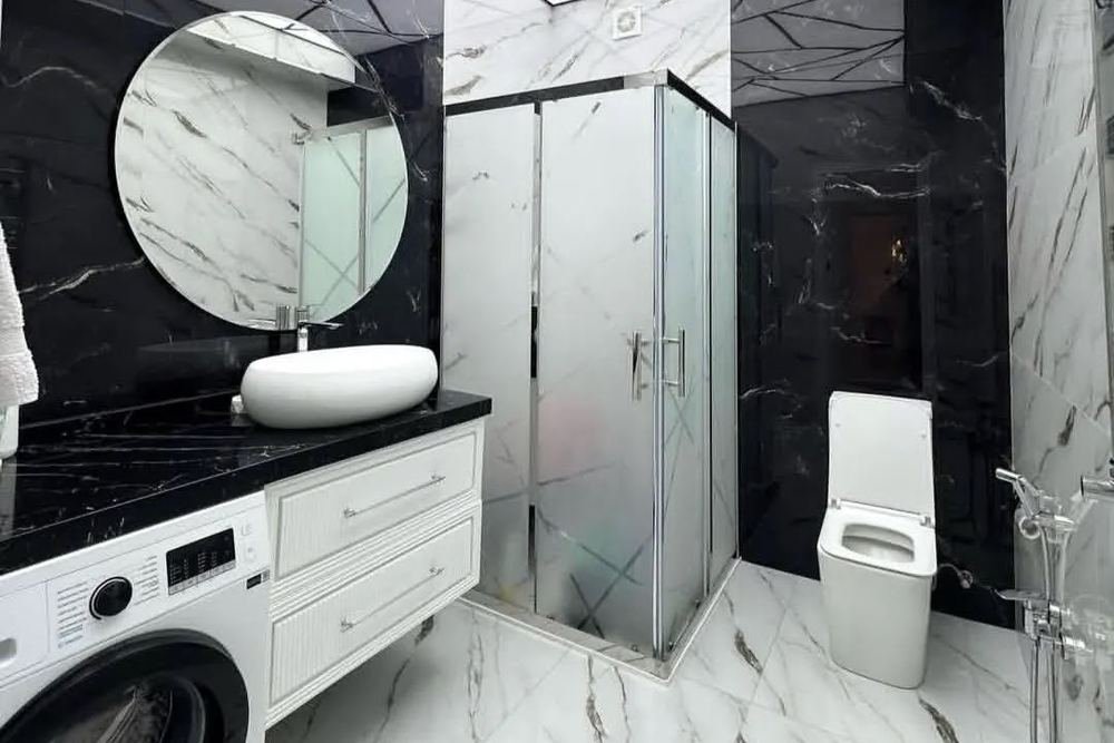 A black and white marble bathroom with a round mirror
