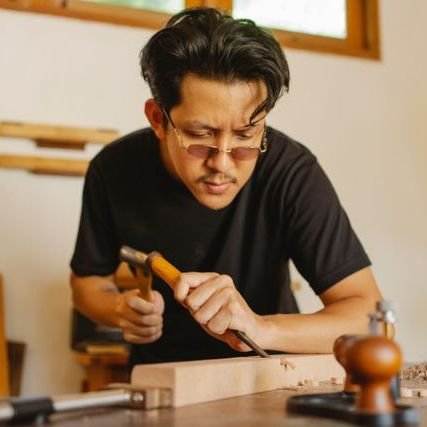 A carpenter shaping wood with a chisel