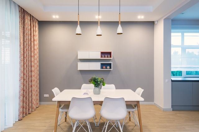 A dining area with a white table and pendant lights