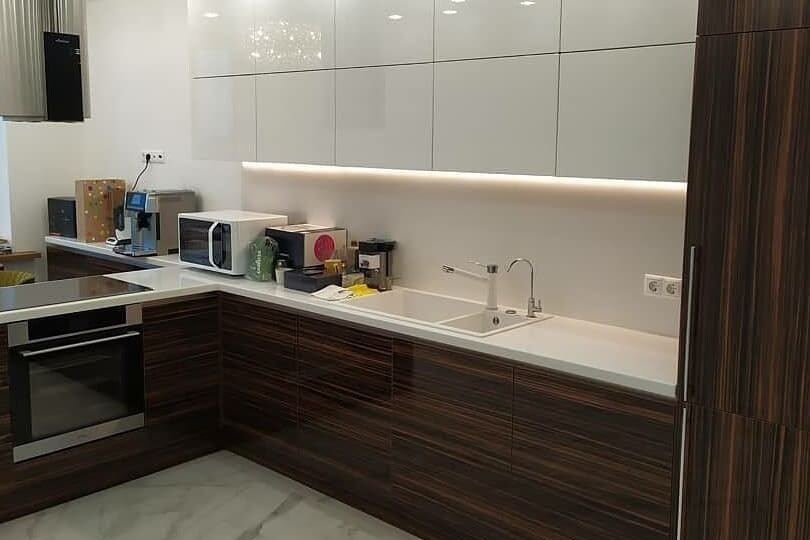 A kitchen with dark walnut units and white gloss wall cupboards
