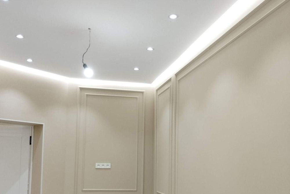 A room with beige wall panelling and a recessed, lit ceiling
