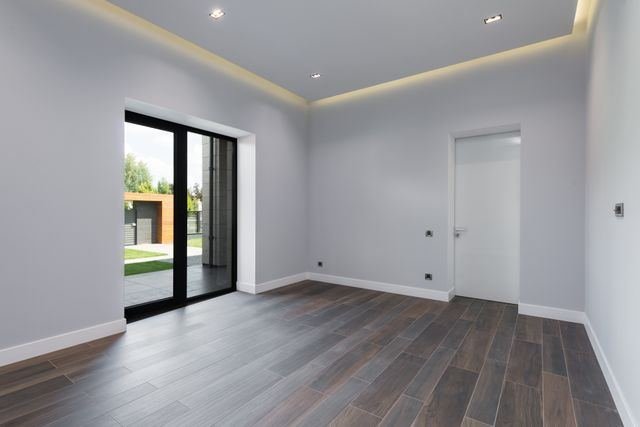 An empty reception room with grey walls and a dark wood floor