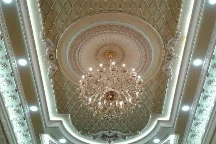 An ornate plaster ceiling with a chandelier