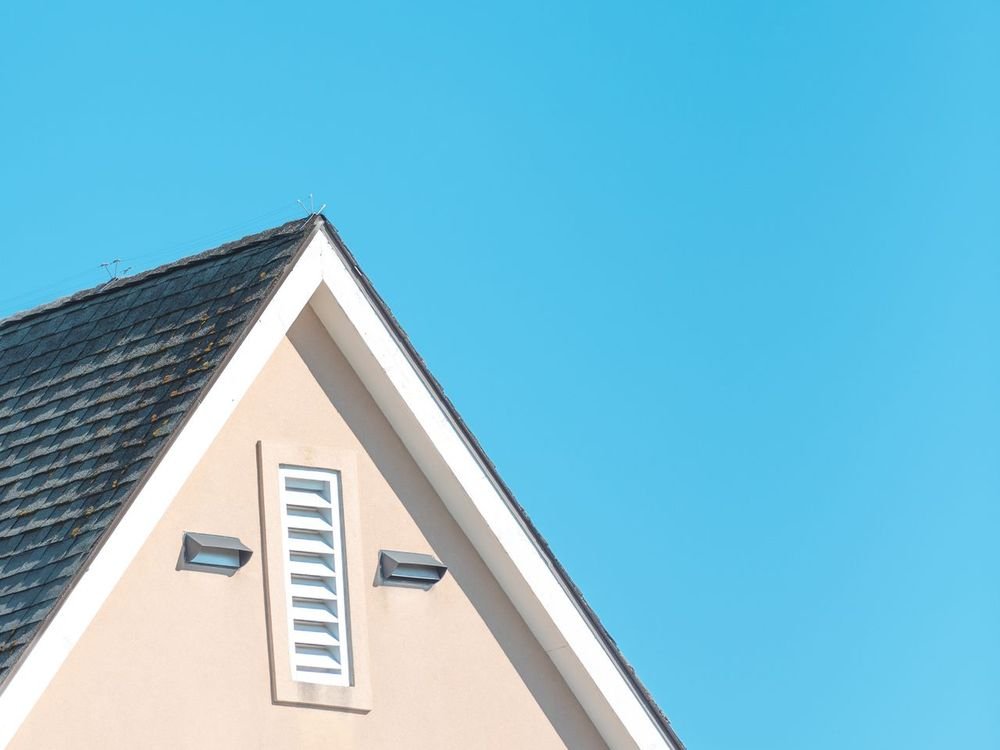 The tiled gable end of a house against a blue sky