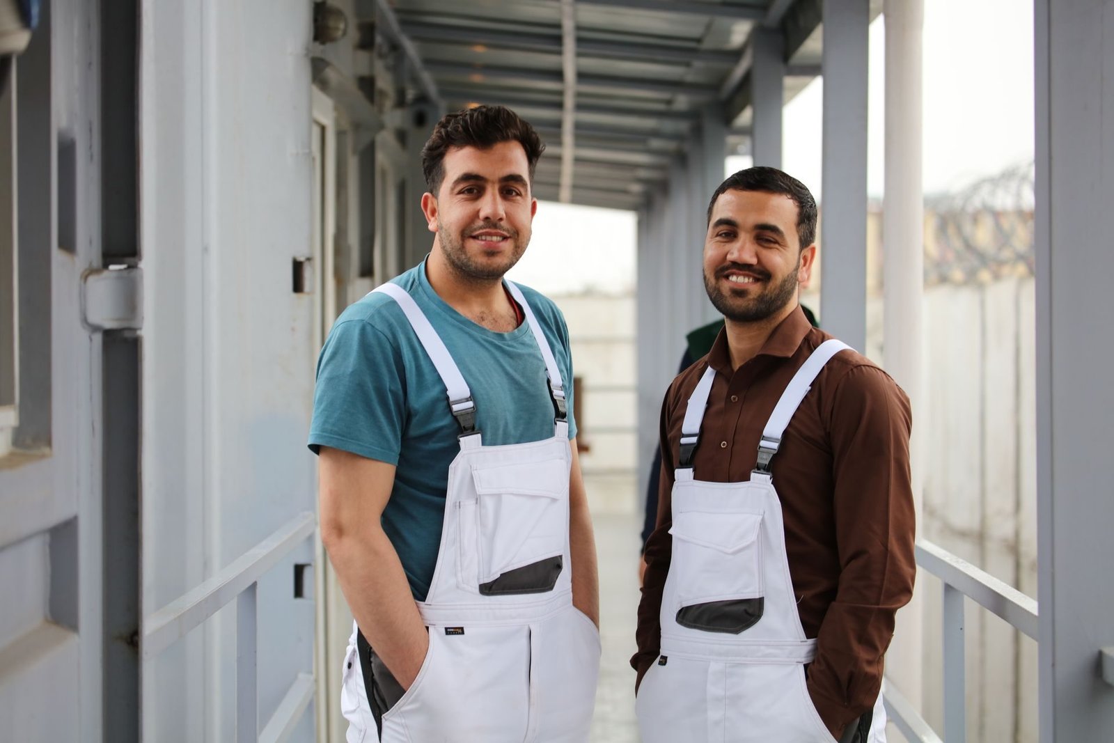 Two smiling workers in white overalls